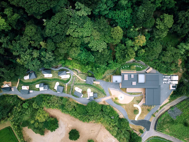 Aerial view of the slate roofs and striped terraced landscape nestled within dense forest canopy