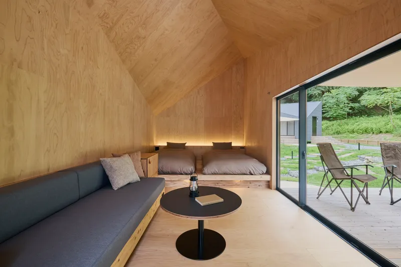 Plywood-lined sleeping loft with built-in platform bed and sliding glass door to deck