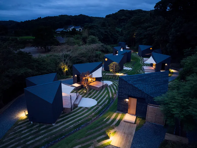 Elevated night view of the cluster of illuminated volumes scattered across the sloped landscape