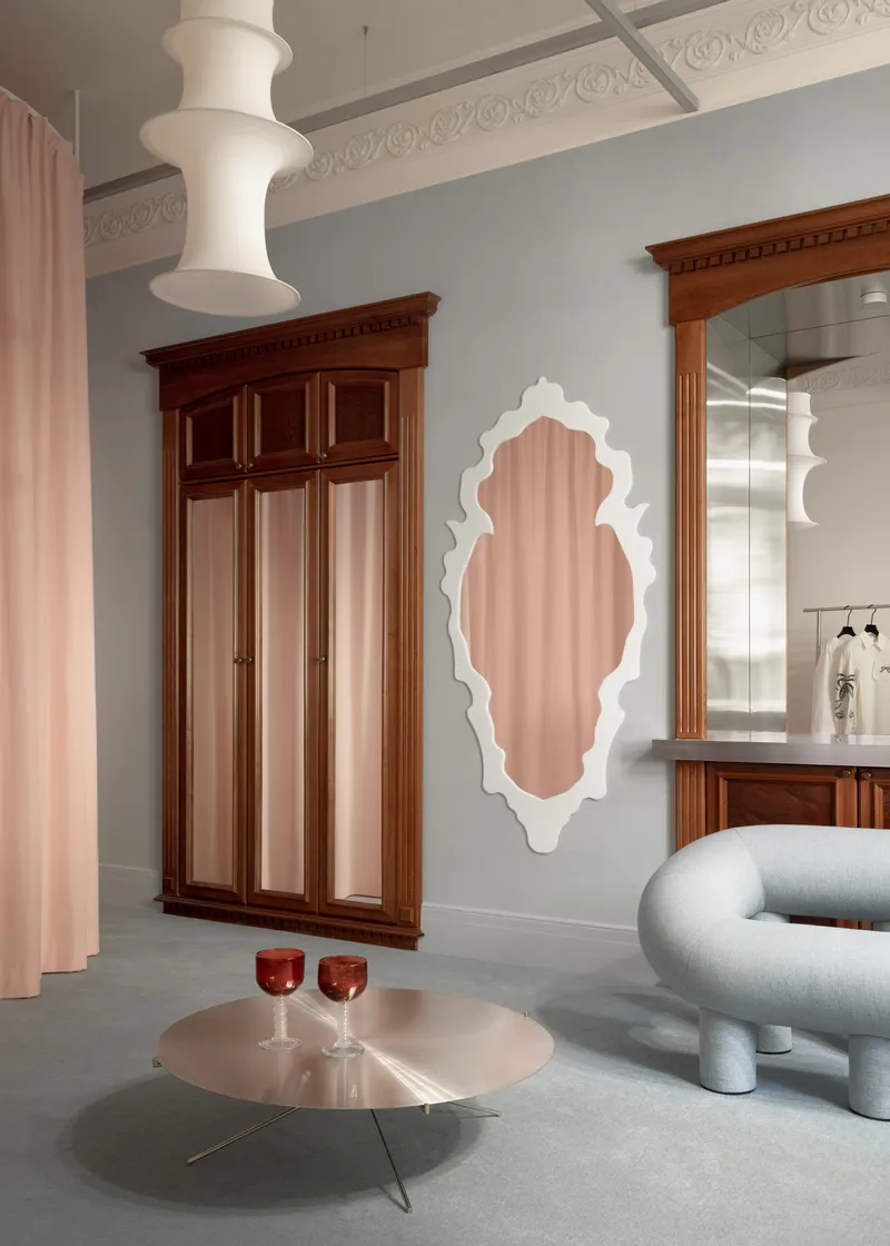 Ornamental mirror and vintage wooden wardrobe against a grey wall beneath decorative ceiling molding