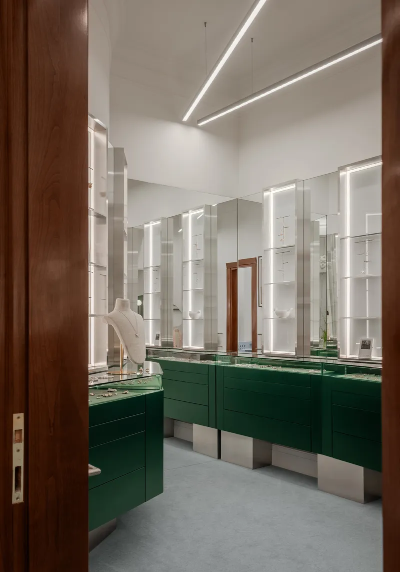 Interior view through timber doorway of retail space with green lacquered display cases and backlit white shelving