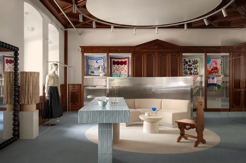 Gallery space with wood paneling, circular ceiling detail and ribbed metal furniture under track lighting