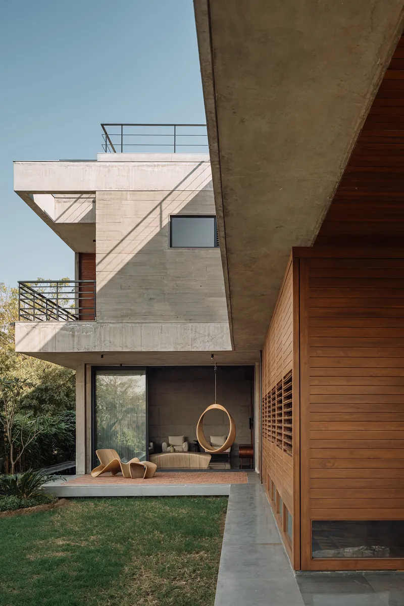Stacked concrete volumes with timber cladding framing ground-floor living space overlooking lawn
