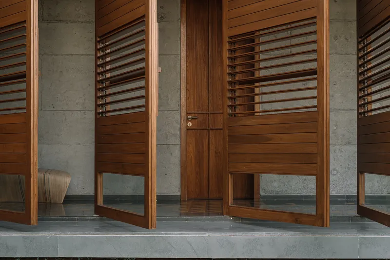 Entry threshold showing timber louvered doors between concrete columns and polished concrete floor