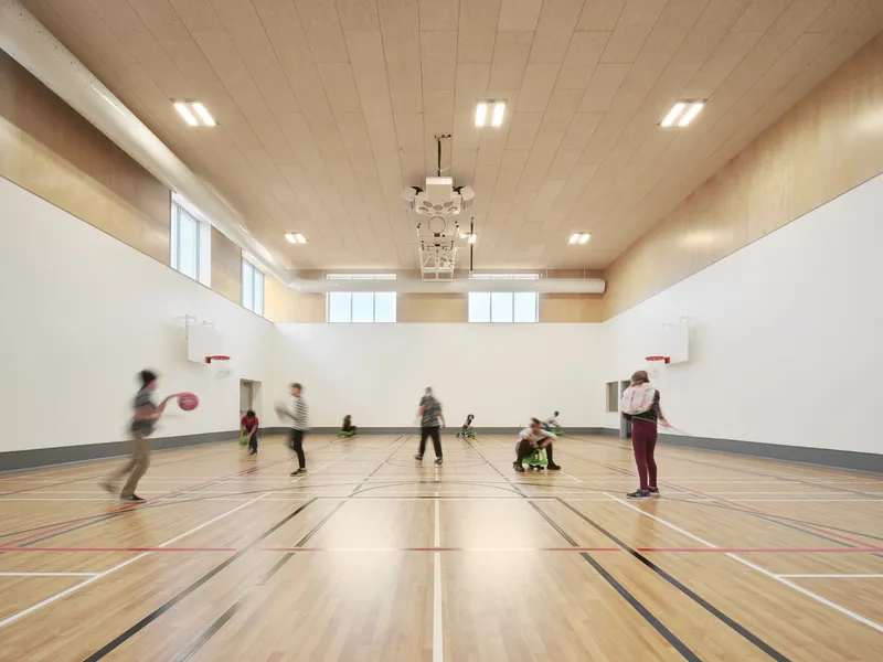 Gymnasium with timber floor and plywood ceiling where children play basketball in motion blur