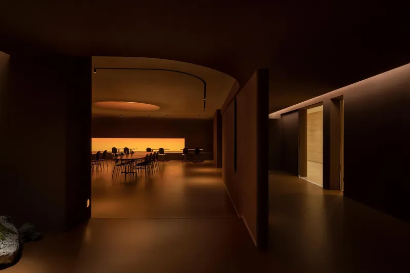 Curved corridor leading to a seating area with backlit amber wall at the end
