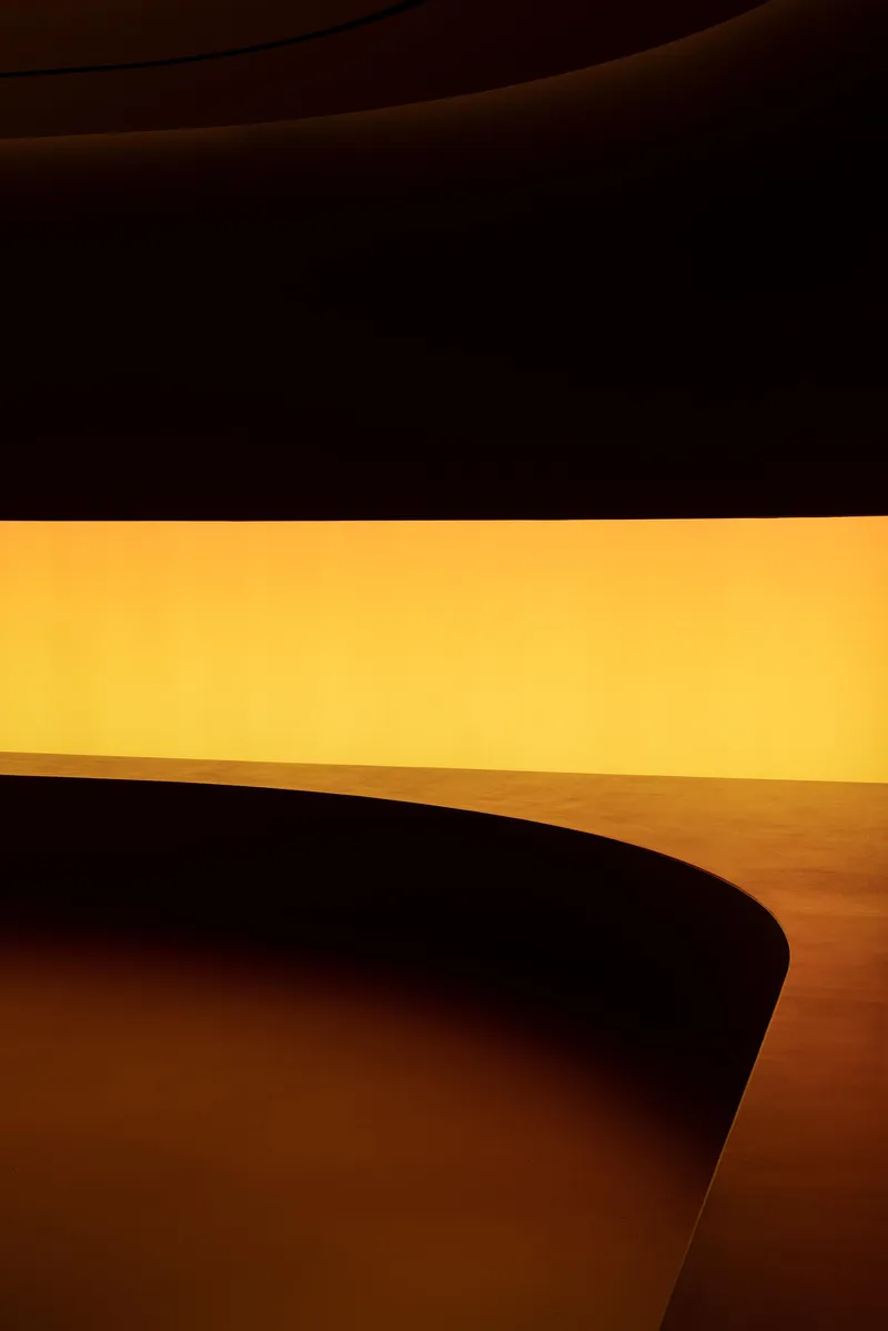 Close-up of curved wall edge against an amber illuminated vertical surface