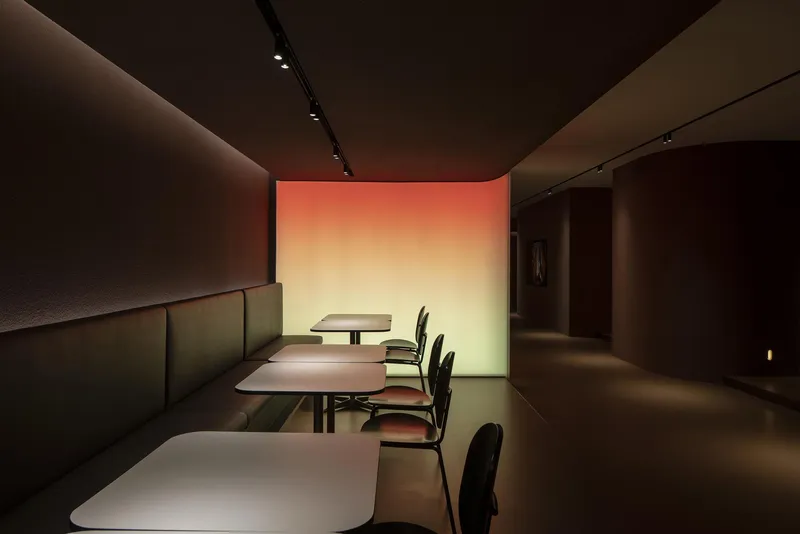 Banquette seating along a low partition wall beneath a gradient light panel