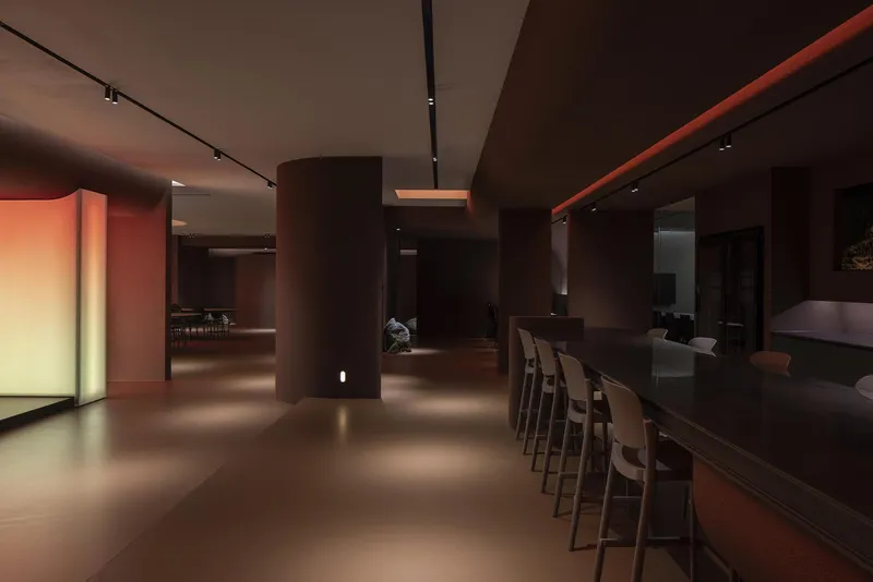 Open interior with cylindrical columns and bar seating along a continuous counter under track lighting