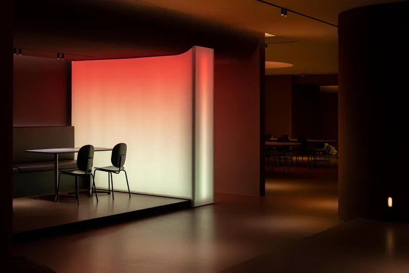 Seating nook with two chairs and table against a gradient illuminated wall in warm tones
