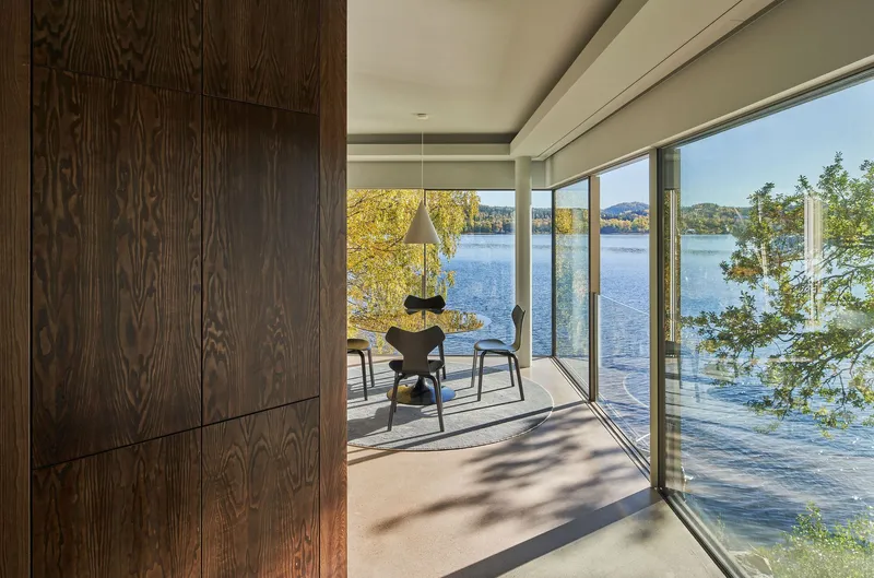 Interior with dark wood paneling and sliding glass doors opening to a lakeside terrace