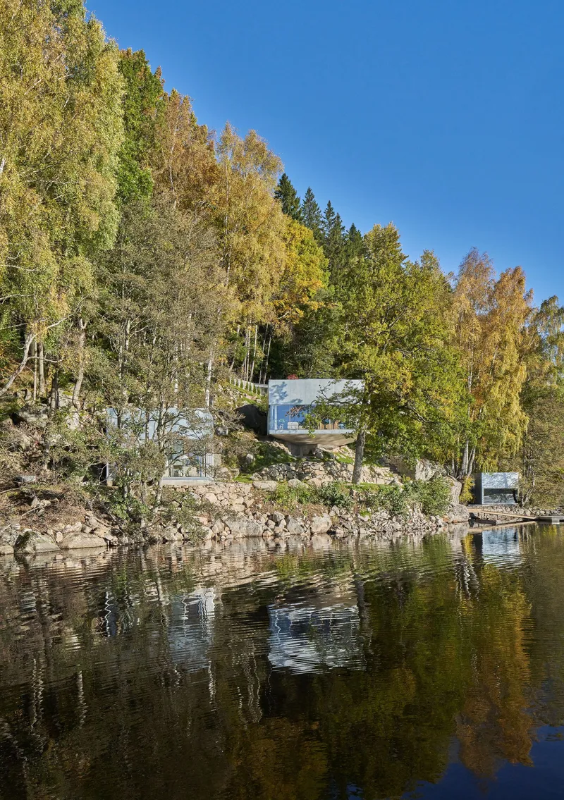 Waterside pavilions set into the wooded hillside among autumn birches and evergreens