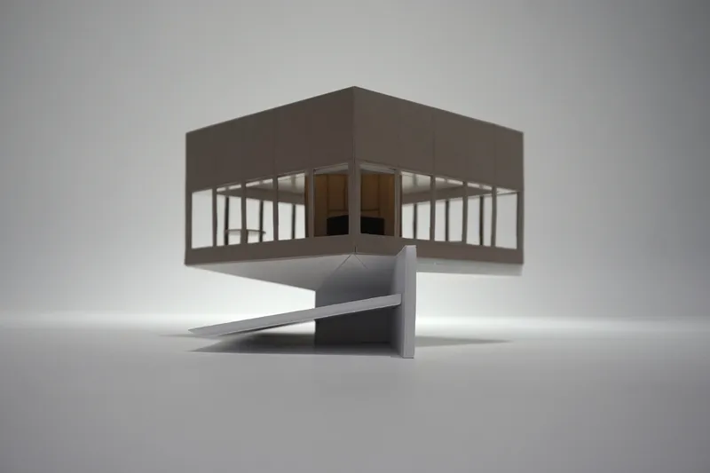 Physical model of an elevated pavilion on a concrete pedestal with a folded access ramp