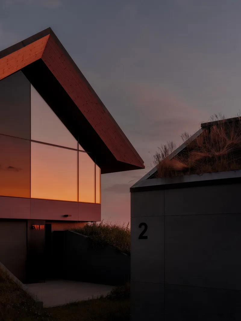 Gabled facade with timber cladding and glowing interior light at twilight
