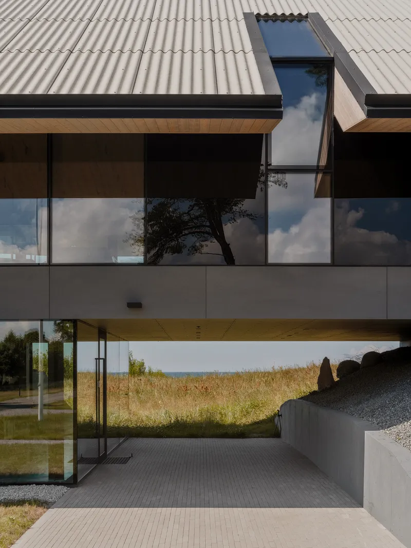 Covered entry passage with timber ceiling soffit framing a view of the grassy dunes beyond