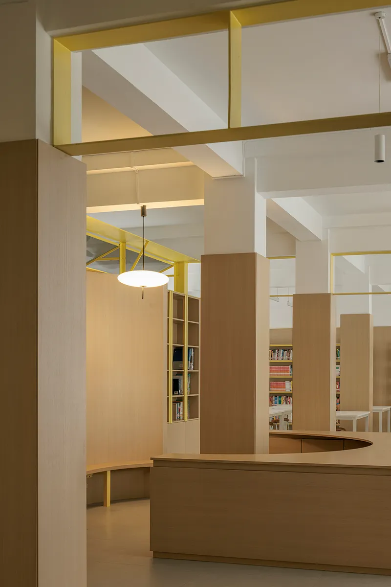 Interior circulation desk with yellow-framed ceiling coffers and light wood built-in shelving