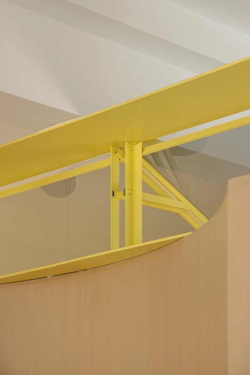 Close-up of yellow steel beam connection with diagonal bracing against white ceiling