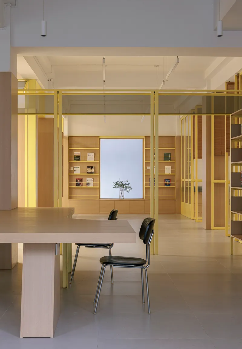 Reading area with yellow steel structural frame and central window flanked by oak shelving