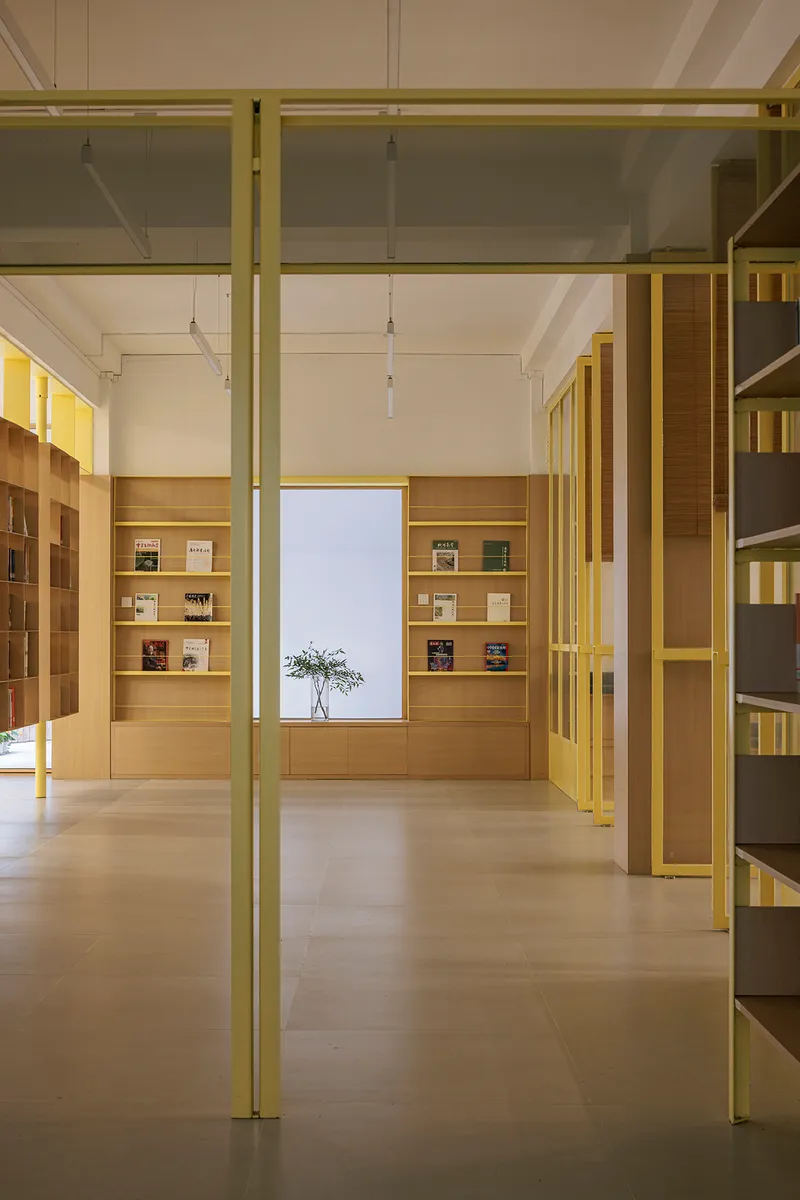 Library interior with yellow steel structural columns and light oak floor-to-ceiling bookshelves