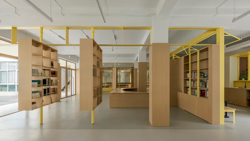 Interior library space with freestanding timber shelving units and yellow steel frames under exposed ceiling beams