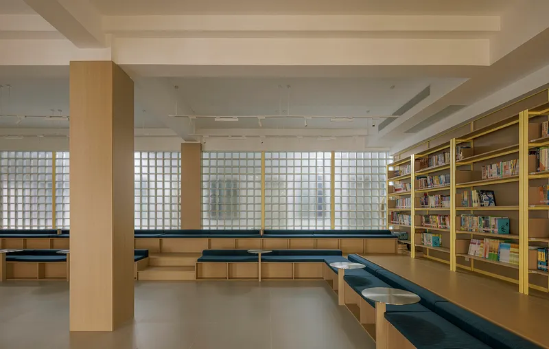 Reading area with stepped seating below translucent glass block windows filtering daylight