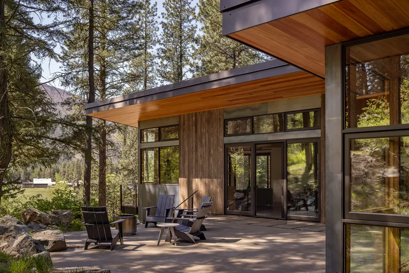 Concrete terrace with timber-framed glazing and cedar soffit overlooking the forest with outdoor seating