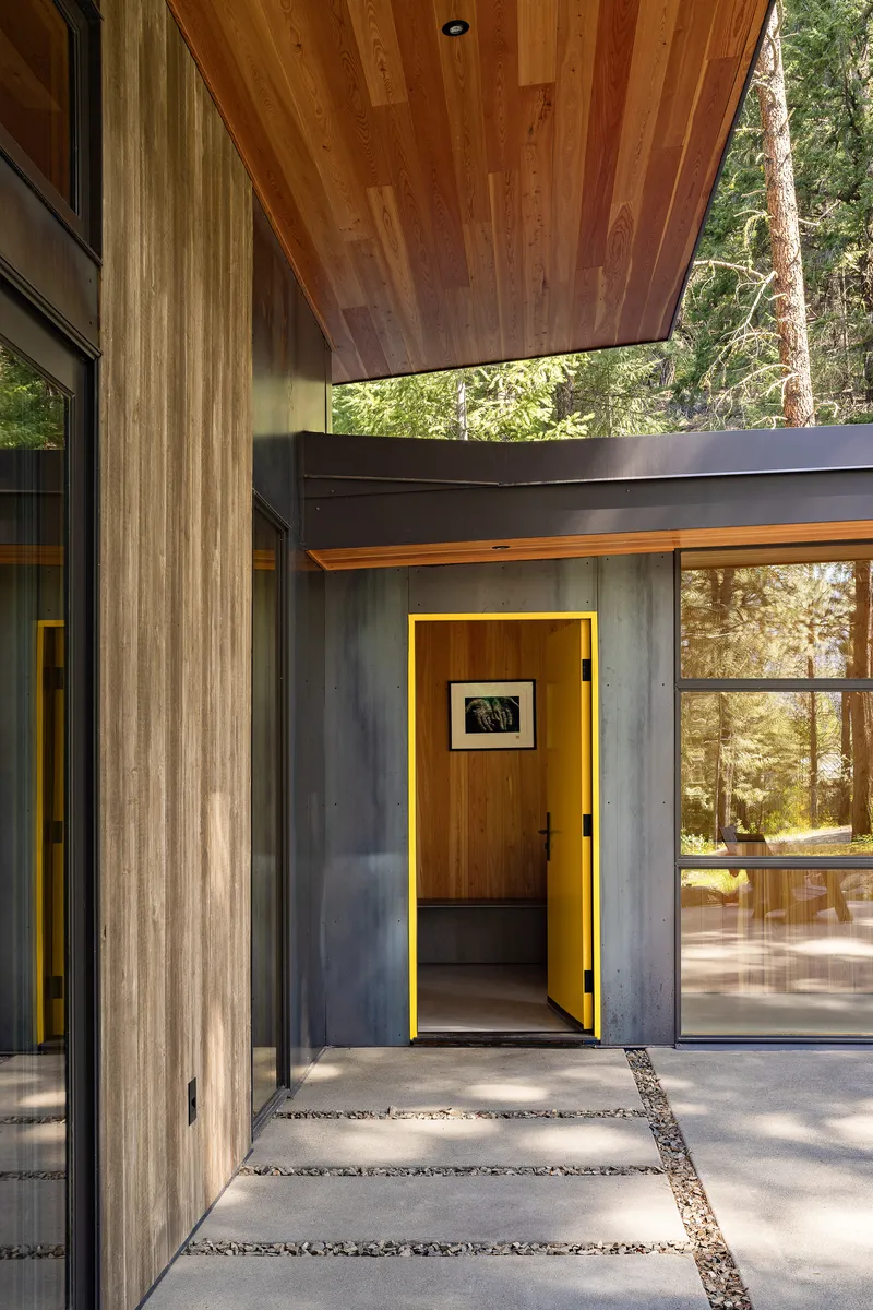 Covered courtyard with concrete pavers and yellow-painted doorway framed by weathered timber walls