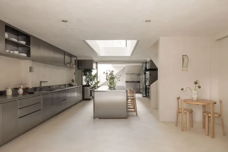 Open kitchen with stainless steel cabinetry and island beneath a rectangular skylight
