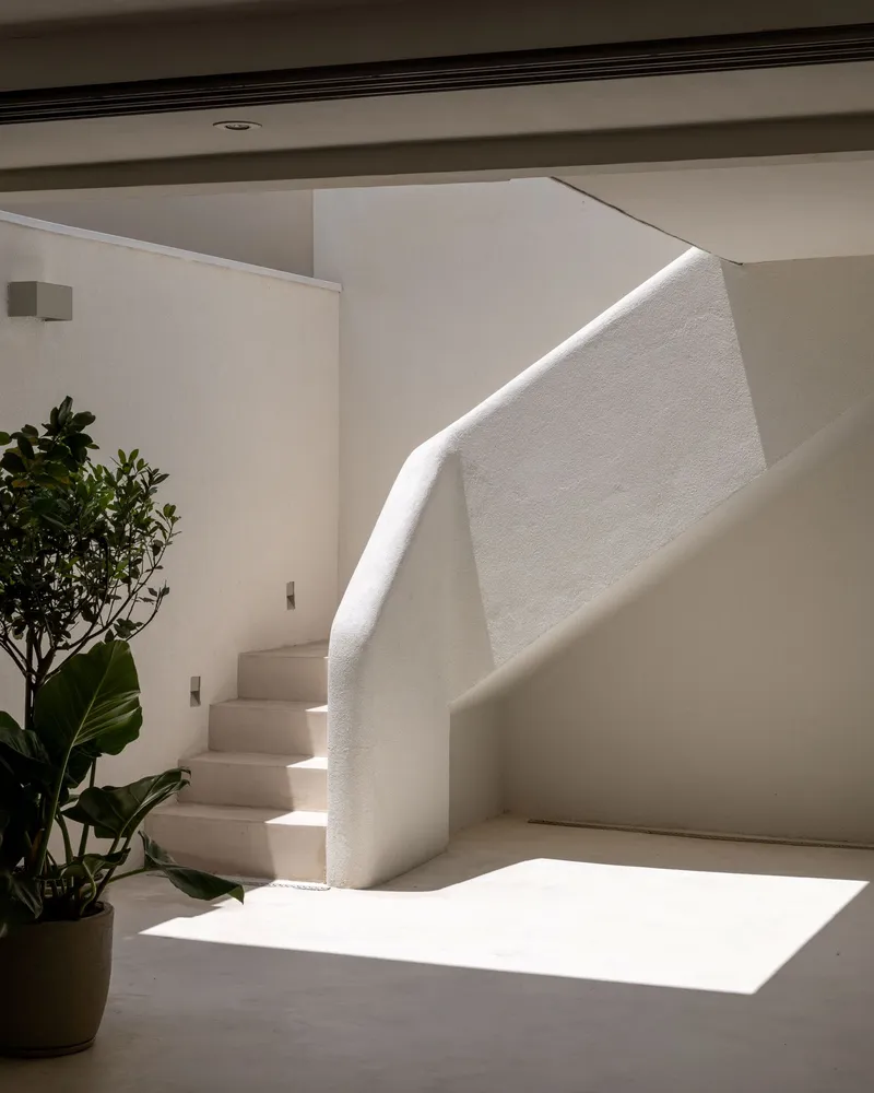 White plastered staircase with integral handrail illuminated by natural light from above