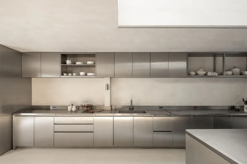 Stainless steel kitchen cabinetry with integrated sink and open shelving niches