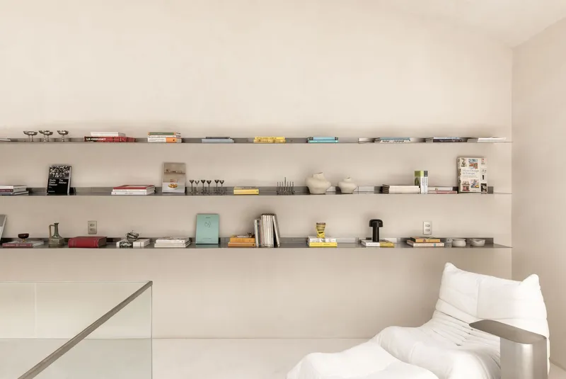 Built-in shelving spanning the wall displaying books and glassware above a white sofa