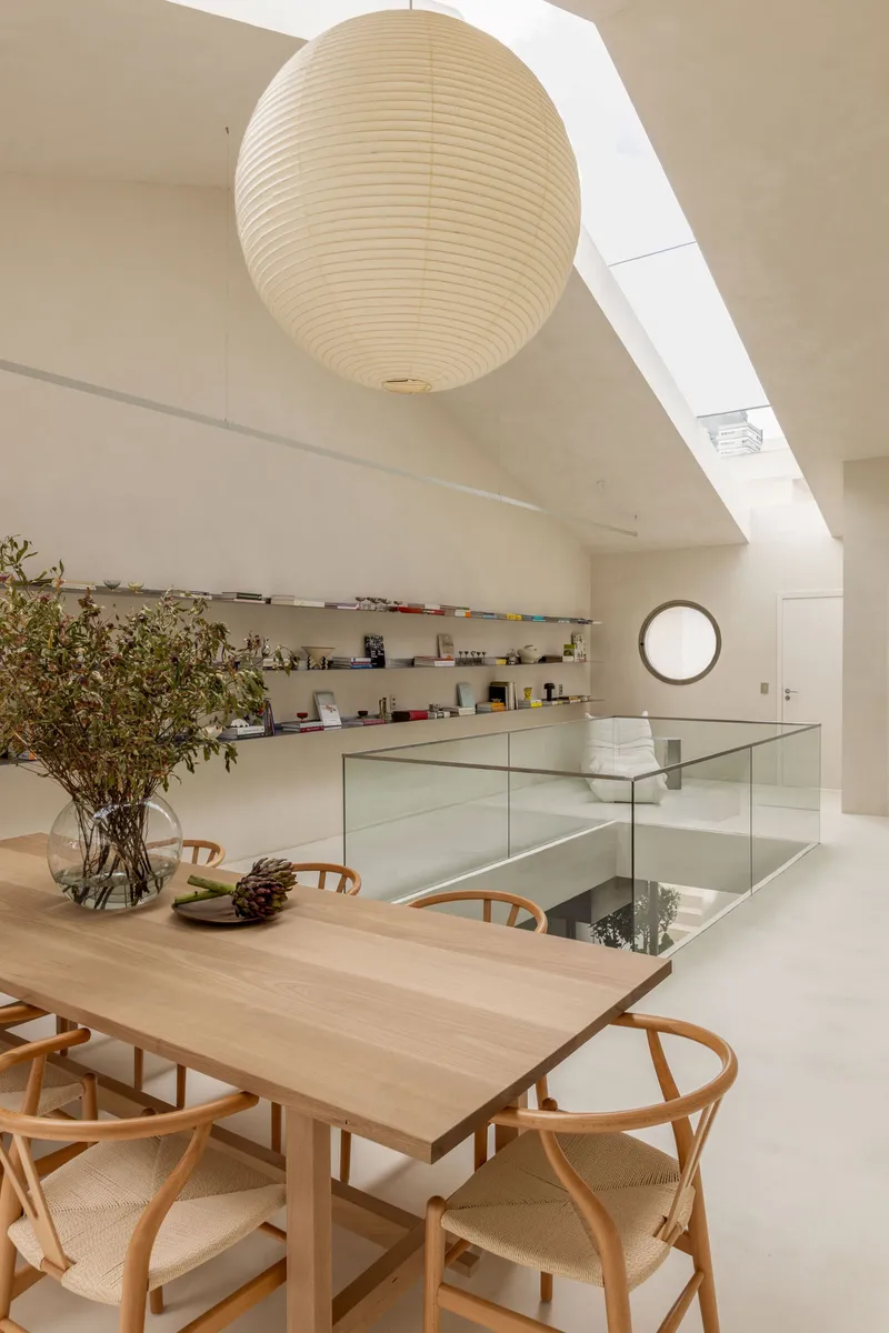 Paper sphere pendant over dining table with glass-edged opening to floor below