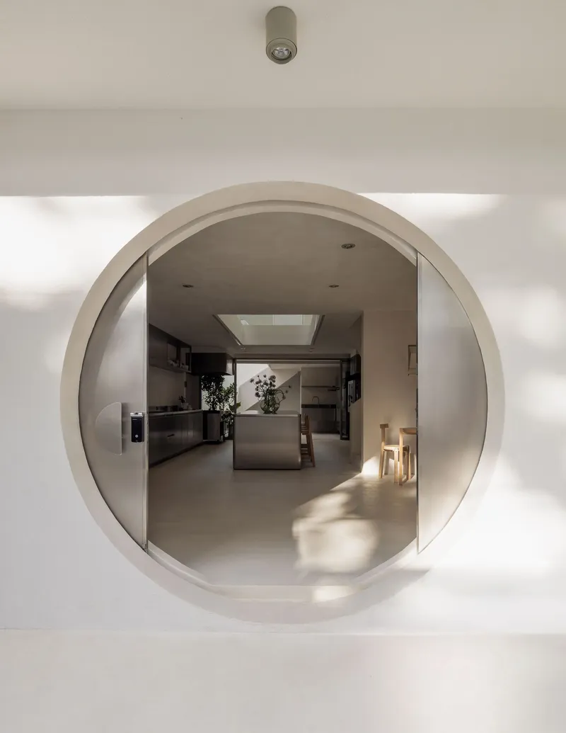 Circular portal framing view through to kitchen with skylight beyond