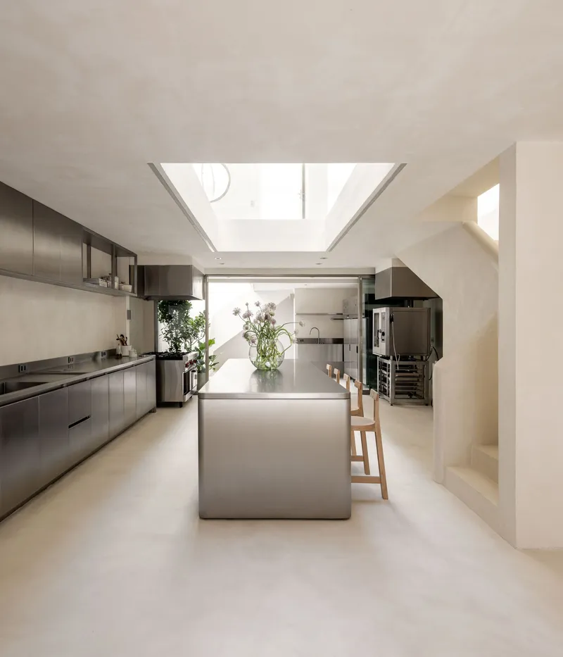 Galley kitchen with stainless steel island and cabinetry beneath central skylight