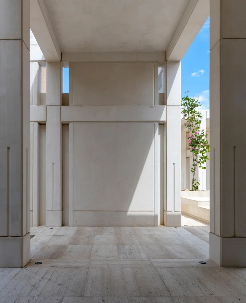 Stone passage framing a vertical slot of sky and a flowering vine at the threshold
