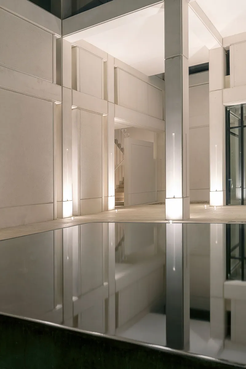 Reflecting pool mirroring illuminated wall panels and columns in an interior atrium at night