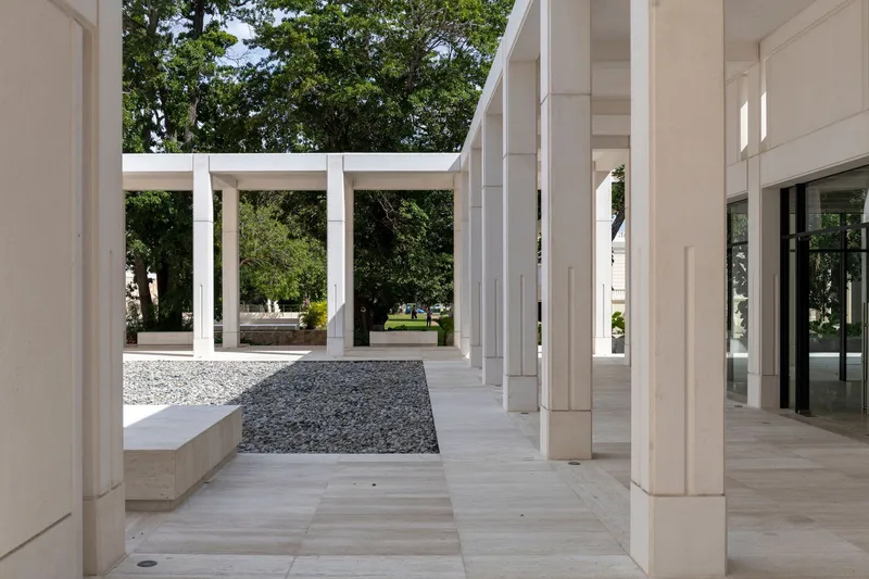 Colonnade intersection with gravel courtyard insert framed by white stone columns and pavers