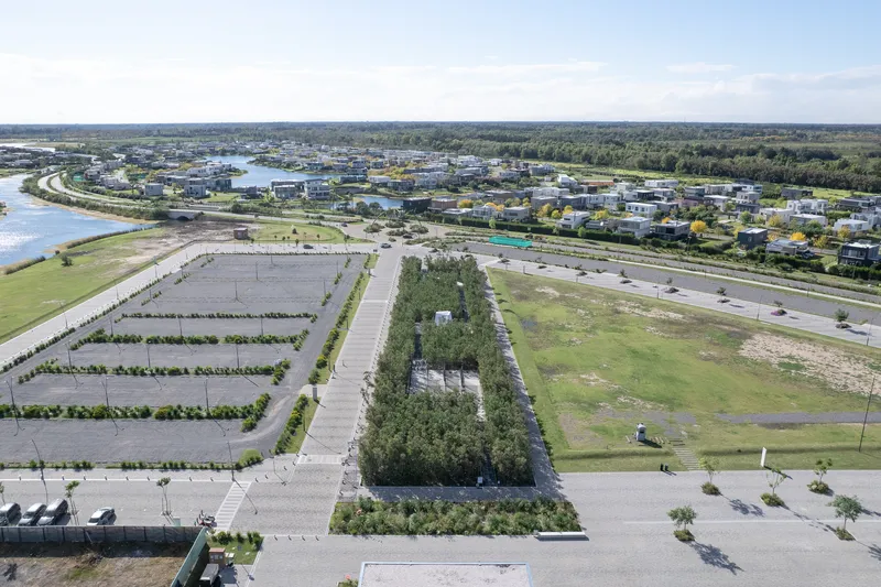 Aerial view of tree-planted median and paved parking lots extending toward suburban waterfront horizon