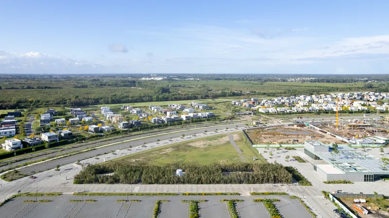 Aerial view of a residential development with scattered housing and construction zones beyond planted rows