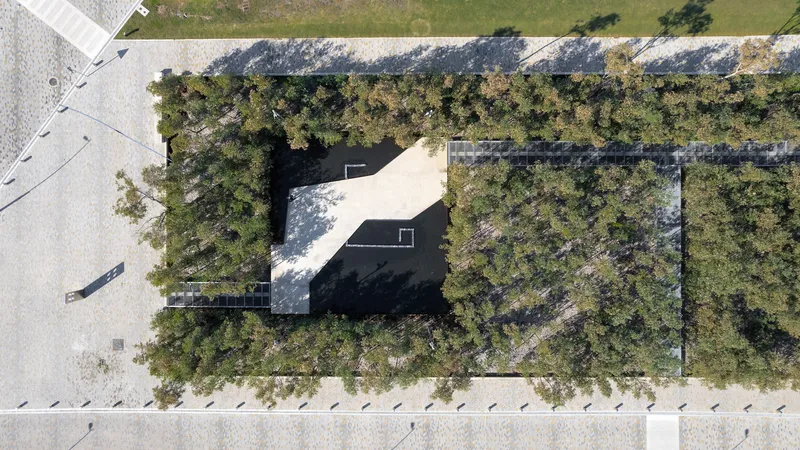Overhead view of a building with a perforated roof nested within a wooded site
