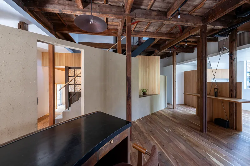 Open living space with exposed timber structure and skylights framing volumes of white plaster