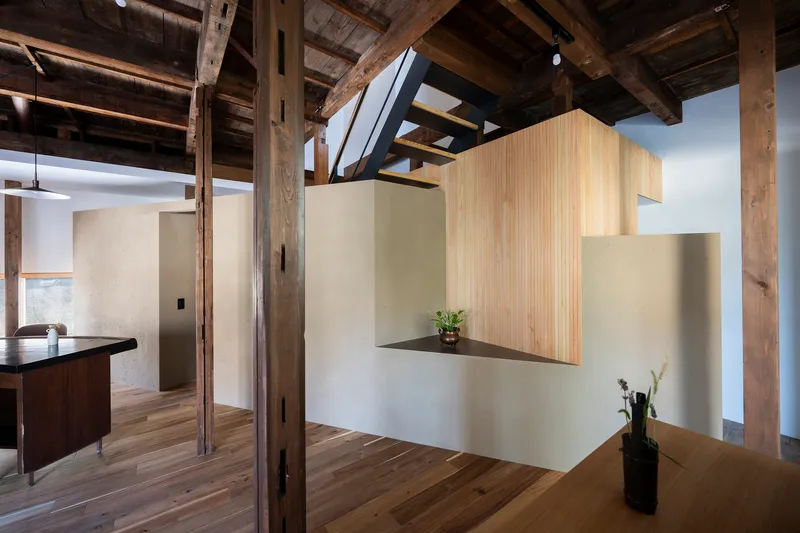 Interior view showing reclaimed timber post-and-beam structure with white plaster walls and vertical grain wood cabinetry