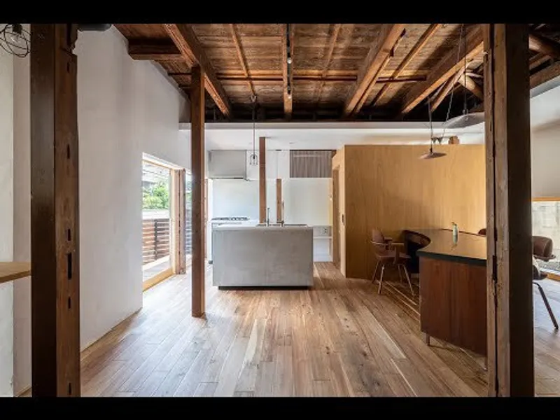 Open-plan kitchen and dining space with exposed timber frame and joinery beneath a natural wood ceiling