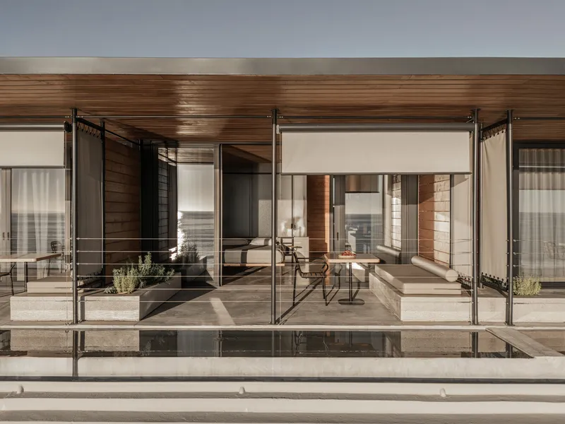 Glass-enclosed terrace with sliding panels and timber ceiling opening onto a reflecting pool