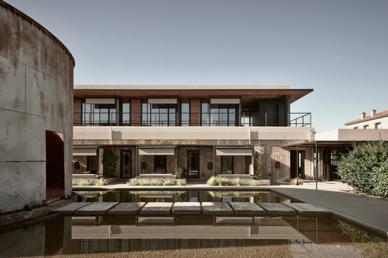 Courtyard pool with stepping stones reflecting the concrete cylinder and two-story residential wings