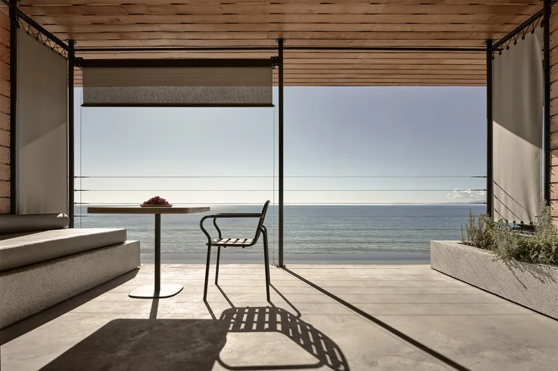 Open terrace with steel frame canopy and single chair overlooking the ocean horizon