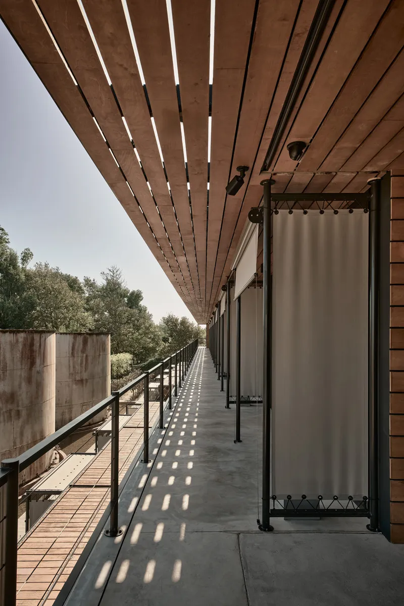 Covered walkway with slatted timber overhang casting striped shadows on concrete floor
