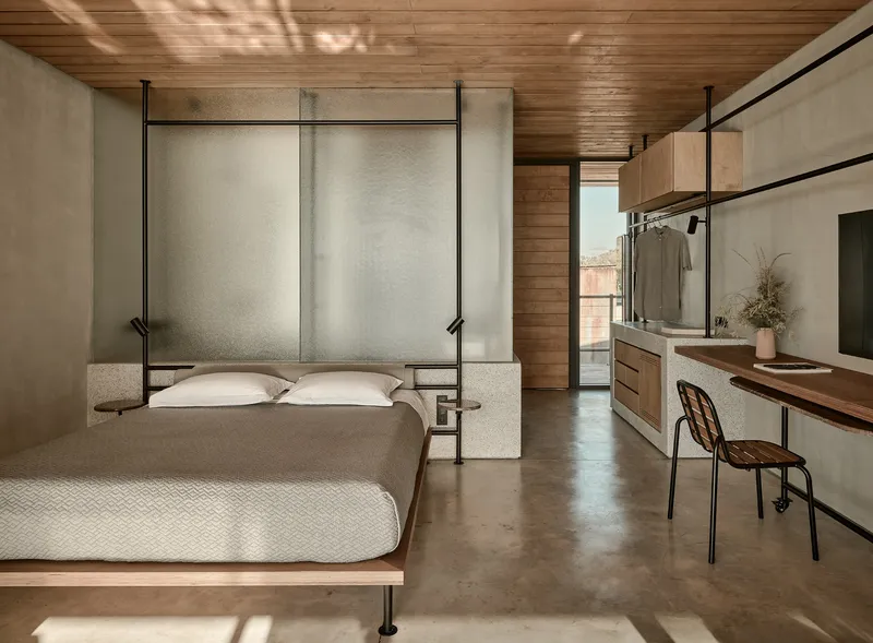 Bedroom with translucent panel headboard and concrete partition beneath slatted timber ceiling