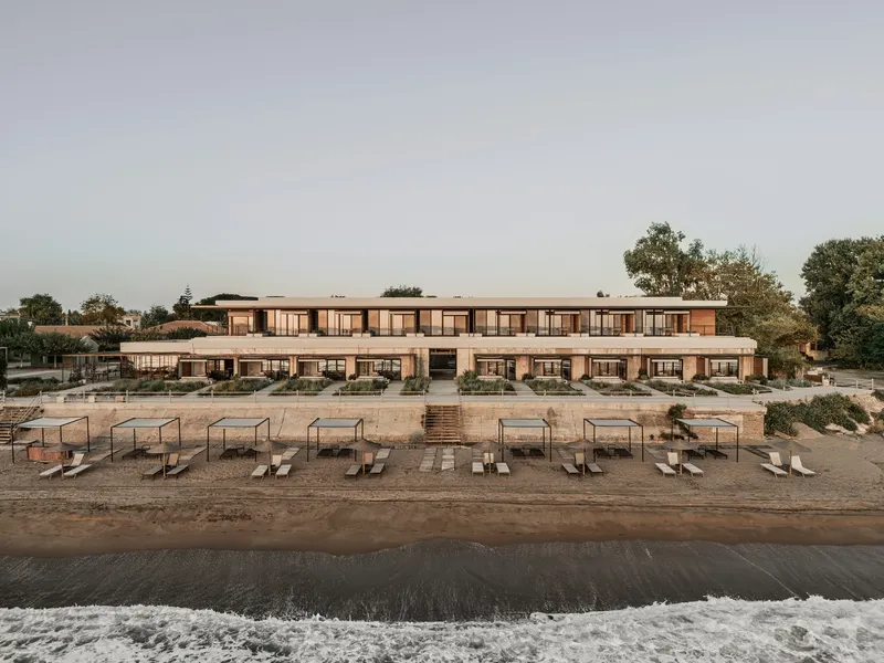 Beachfront facade with rows of lounge chairs on sand and gentle surf at dusk