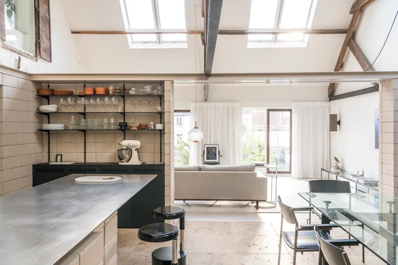 Open-plan kitchen and dining space with exposed timber roof trusses and large skylights overhead